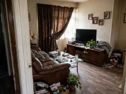 Altes, möbliertes Wohnzimmer mit gemustertem Sofa, vor der Neugestaltung