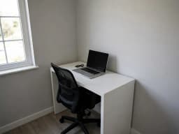 Bare home office corner with a white desk and a laptop, before decorating