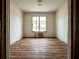 Leerer Raum in einem Altbau mit Heizkörper und Holzboden, vor der Neugestaltung