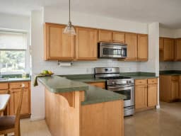 Maple kitchen with green laminate countertops and a peninsula, before redesign