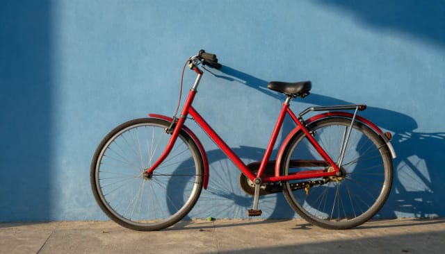 A red bicycle leaning against a blue wall in the late afternoon sun, made from a text prompt with the AI Image Generator