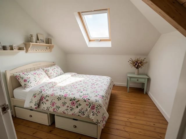 Ein Dachschlafzimmer, neu gestaltet im Cottagecore-Stil, mit geblümter Bettwäsche und Trockenblumen